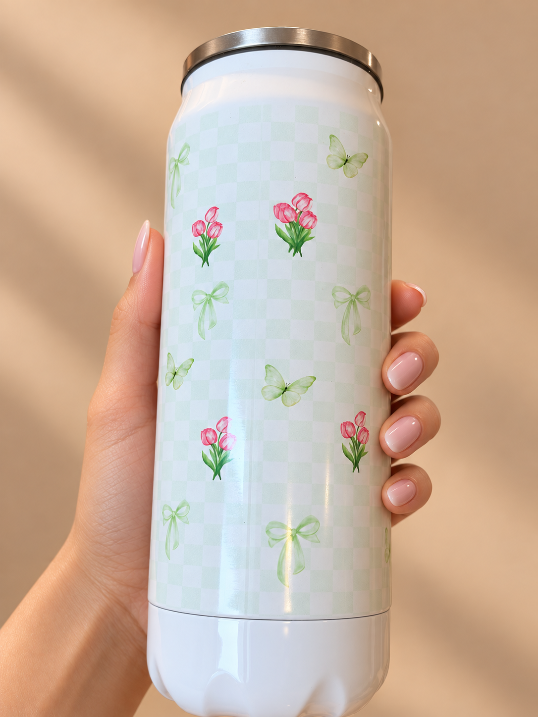 Fiora floral metal can sipper held in hand, with pink tulips, green bows and butterflies on pale green checks. Shop Kamashh India